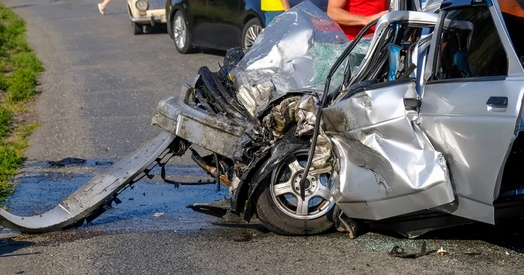Severely damaged car after high-speed crash with front end crushed on roadside.
