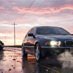 A blue car drives away from an overturned vehicle and a "Hit & Run Case" sign on a wet road