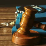 Judge’s gavel and handcuffs placed on law books symbolizing legal consequences.