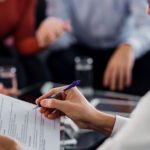 Professional reviewing legal documents with a pen while meeting with clients.